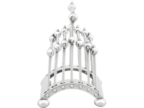 fig 1. An Edwardian sterling silver toast rack featuring a curved base and fan-shaped radiating dividers topped with spherical details.
