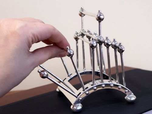 fig 5. An Edwardian sterling silver toast rack featuring a curved base and fan-shaped radiating dividers topped with spherical details.