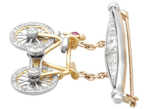 fig 4. An antique Edwardian bar brooch featuring a suspended yellow gold bicycle with diamond-set wheels, set beneath a platinum-faced bar set with diamonds.
