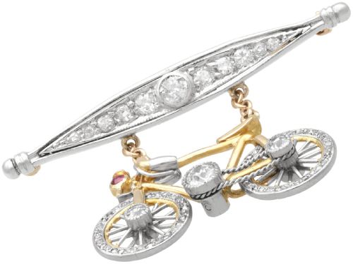 fig 5. An antique Edwardian bar brooch featuring a suspended yellow gold bicycle with diamond-set wheels, set beneath a platinum-faced bar set with diamonds.