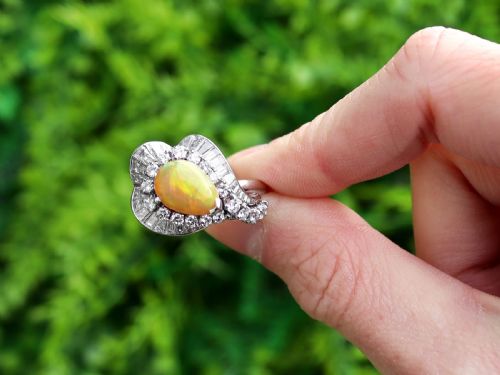 fig 1. A platinum dress ring featuring a central pear-shaped orange opal surrounded by a halo of round and baguette-cut diamonds in an asymmetrical frame.