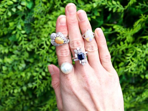 fig 2. A platinum dress ring featuring a central pear-shaped orange opal surrounded by a halo of round and baguette-cut diamonds in an asymmetrical frame.