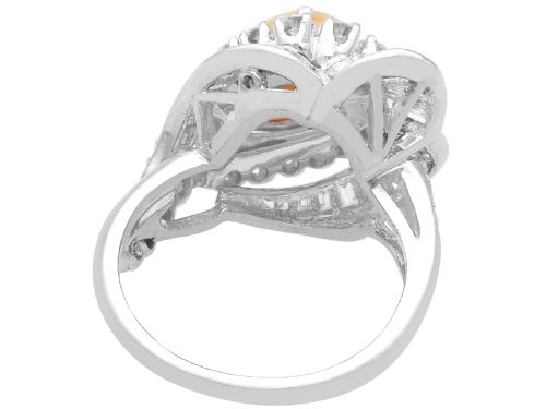 fig 9. A platinum dress ring featuring a central pear-shaped orange opal surrounded by a halo of round and baguette-cut diamonds in an asymmetrical frame.