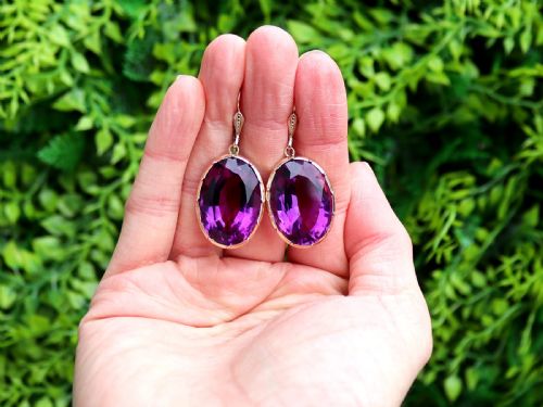 fig 1. A pair of antique 9ct gold drop earrings featuring large oval faceted purple amethysts on leverback ear wires.