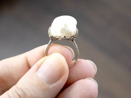 fig 7. An antique platinum dress ring featuring a large, smooth natural blister pearl flanked by diamond-set shoulders.
