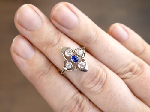 fig 4. An Art Deco 14ct yellow gold ring featuring a central oval blue sapphire surrounded by four round diamonds set in a diamond-shaped openwork frame.