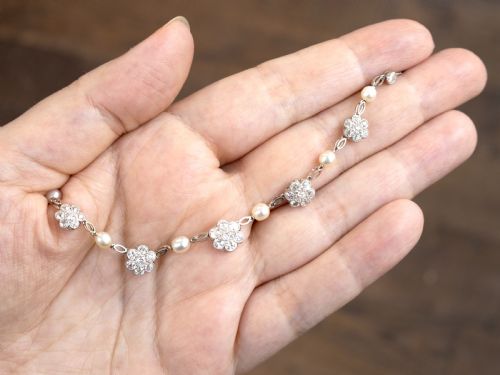 fig 3. An Edwardian platinum chain necklace set with diamond floral clusters and interspersed with round white pearls.