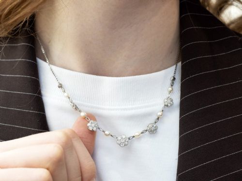 fig 4. An Edwardian platinum chain necklace set with diamond floral clusters and interspersed with round white pearls.