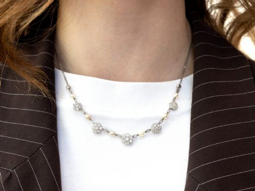 fig 5. An Edwardian platinum chain necklace set with diamond floral clusters and interspersed with round white pearls.