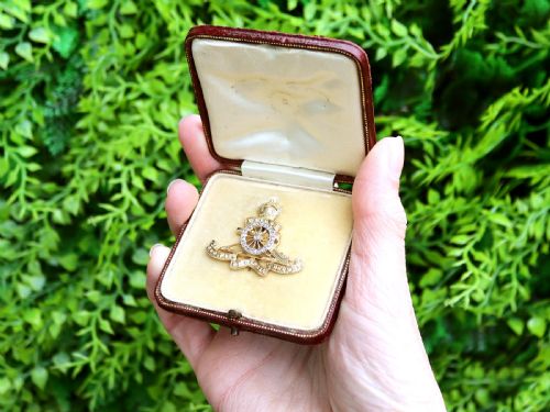 fig 1. An 18ct yellow gold Royal Artillery brooch featuring a diamond-set gun wheel, crowned cannon motif, and Latin motto ribbons.