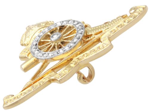 fig 8. An 18ct yellow gold Royal Artillery brooch featuring a diamond-set gun wheel, crowned cannon motif, and Latin motto ribbons.