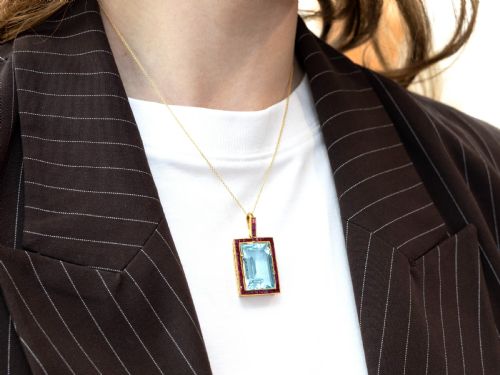 fig 4. A large rectangular step-cut blue aquamarine set in yellow gold with a square-cut red ruby border and ruby-set bail.