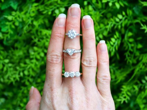 fig 2. A platinum solitaire ring featuring a large round cut central diamond set with six claws, flanked by step-cut baguette diamonds on each shoulder.