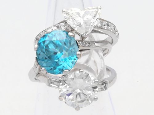 fig 3. A platinum solitaire ring featuring a large round cut central diamond set with six claws, flanked by step-cut baguette diamonds on each shoulder.