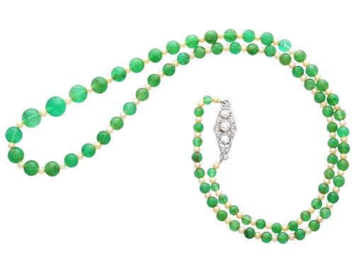 fig 9. An antique single strand necklace displaying alternating green emerald beads and cream pearls connected to a geometric platinum and diamond clasp.