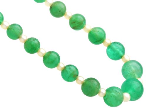 fig 10. An antique single strand necklace displaying alternating green emerald beads and cream pearls connected to a geometric platinum and diamond clasp.