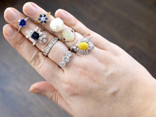 fig 3. An 18ct yellow gold ring featuring a central round diamond surrounded by six oval blue sapphires and outer round diamond accents arranged in a flower motif.