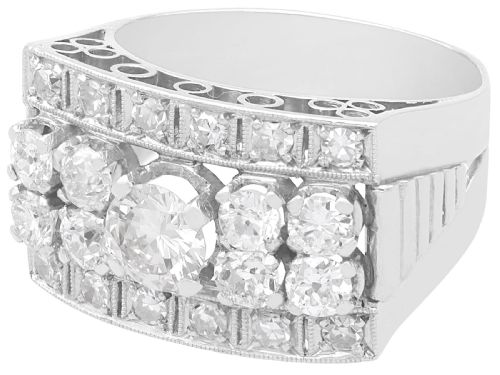 fig 4. An Art Deco platinum dress ring featuring a central round diamond bordered by multiple smaller old-cut diamonds in a geometric rectangular mount with millegrain edges.