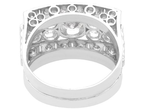 fig 5. An Art Deco platinum dress ring featuring a central round diamond bordered by multiple smaller old-cut diamonds in a geometric rectangular mount with millegrain edges.
