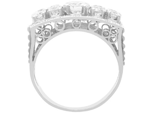 fig 6. An Art Deco platinum dress ring featuring a central round diamond bordered by multiple smaller old-cut diamonds in a geometric rectangular mount with millegrain edges.