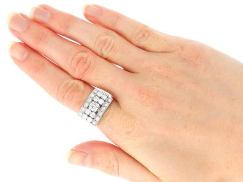 fig 7. An Art Deco platinum dress ring featuring a central round diamond bordered by multiple smaller old-cut diamonds in a geometric rectangular mount with millegrain edges.