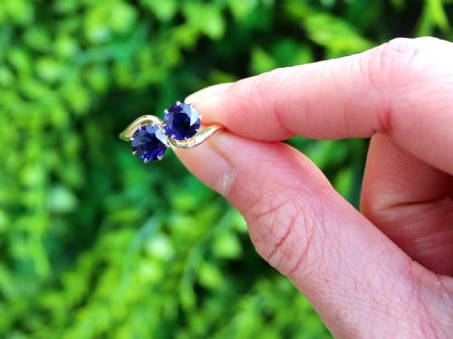 fig 1. An 18ct yellow gold crossover twist ring featuring two round deep blue sapphires set in multi-claw settings.
