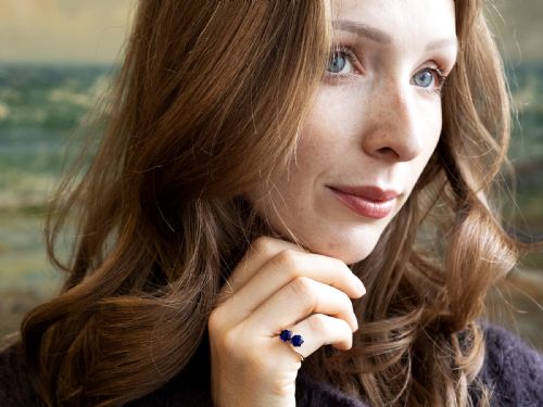 fig 4. An 18ct yellow gold crossover twist ring featuring two round deep blue sapphires set in multi-claw settings.