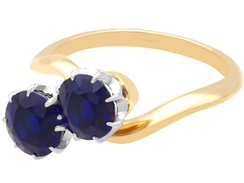 fig 5. An 18ct yellow gold crossover twist ring featuring two round deep blue sapphires set in multi-claw settings.