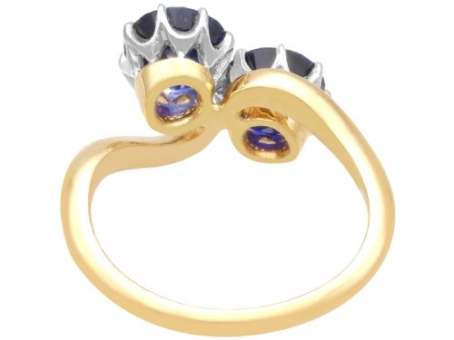 fig 6. An 18ct yellow gold crossover twist ring featuring two round deep blue sapphires set in multi-claw settings.