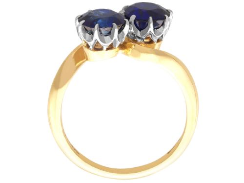 fig 7. An 18ct yellow gold crossover twist ring featuring two round deep blue sapphires set in multi-claw settings.