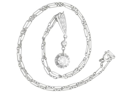 fig 2. An Art Deco platinum drop pendant set with diamonds, featuring a decorative tapered top bail and suspended circular diamond setting on a fine link chain.