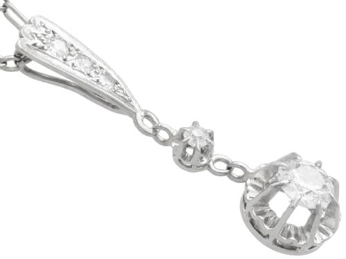 fig 3. An Art Deco platinum drop pendant set with diamonds, featuring a decorative tapered top bail and suspended circular diamond setting on a fine link chain.