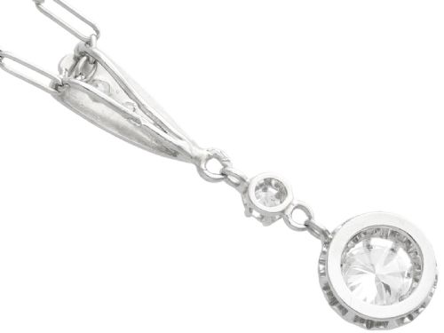 fig 4. An Art Deco platinum drop pendant set with diamonds, featuring a decorative tapered top bail and suspended circular diamond setting on a fine link chain.