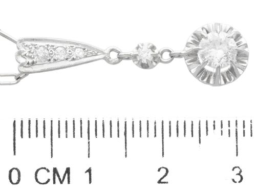 fig 5. An Art Deco platinum drop pendant set with diamonds, featuring a decorative tapered top bail and suspended circular diamond setting on a fine link chain.