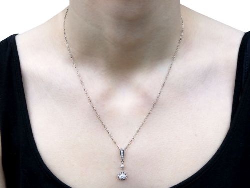 fig 6. An Art Deco platinum drop pendant set with diamonds, featuring a decorative tapered top bail and suspended circular diamond setting on a fine link chain.