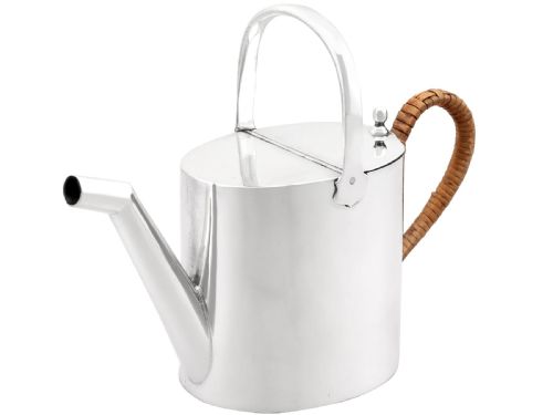 fig 4. An Edwardian sterling silver watering can featuring a cylindrical body, straight spout, overhead loop handle, woven cane side handle, and an engraved central monogram.