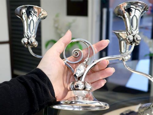 fig 1. A pair of sterling silver two-light Arts and Crafts style candelabra featuring scrolled arms, beaded motifs, and flared sconces on circular bases.