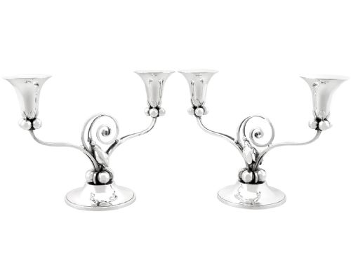 fig 3. A pair of sterling silver two-light Arts and Crafts style candelabra featuring scrolled arms, beaded motifs, and flared sconces on circular bases.