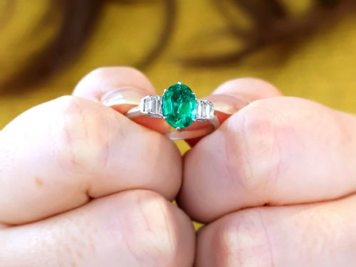 fig 2. An Art Deco platinum dress ring with a central oval green emerald set in claws and flanked by step-cut baguette diamonds on each shoulder.