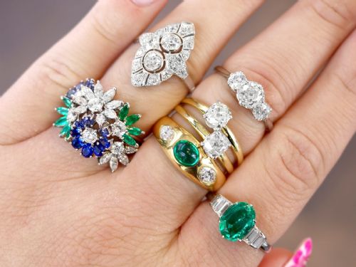 fig 3. An Art Deco platinum dress ring with a central oval green emerald set in claws and flanked by step-cut baguette diamonds on each shoulder.