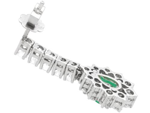 fig 6. A pair of 18ct white gold drop earrings featuring pear-cut green emeralds surrounded by round diamond halos suspended from vertical diamond bars.