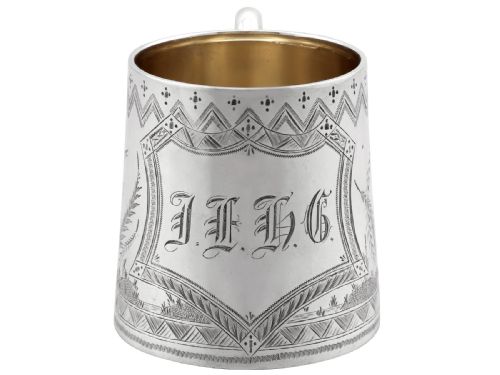fig 3. A tapered sterling silver christening mug featuring hand-engraved foliage and bird motifs, geometric borders, a loop handle, and a gilt interior.