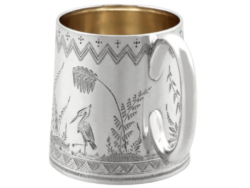 fig 4. A tapered sterling silver christening mug featuring hand-engraved foliage and bird motifs, geometric borders, a loop handle, and a gilt interior.
