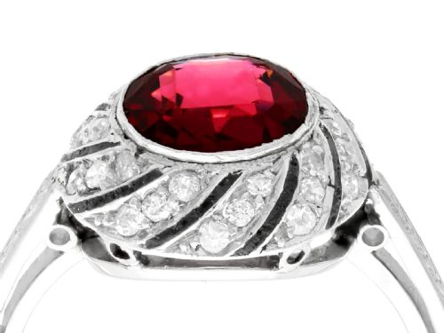 fig 2. An Art Deco platinum dress ring featuring a central round red garnet surrounded by a swirling spiral bezel set with small diamonds.