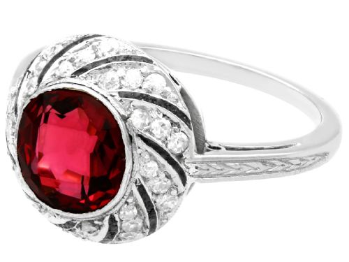 fig 3. An Art Deco platinum dress ring featuring a central round red garnet surrounded by a swirling spiral bezel set with small diamonds.