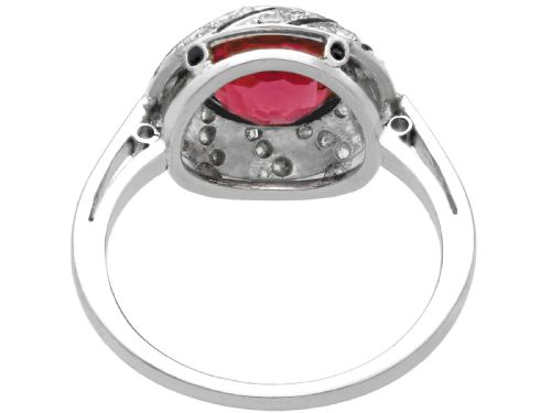 fig 4. An Art Deco platinum dress ring featuring a central round red garnet surrounded by a swirling spiral bezel set with small diamonds.