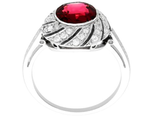 fig 5. An Art Deco platinum dress ring featuring a central round red garnet surrounded by a swirling spiral bezel set with small diamonds.