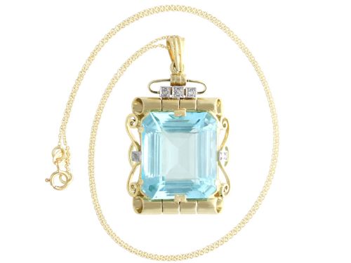 fig 5. A large emerald-cut aquamarine gemstone mounted in a yellow gold scrollwork frame accented with small diamonds and suspended from a chain.