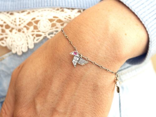 fig 3. An antique platinum link chain charm bracelet featuring diamond-set charms including a running hare, a horseshoe, and a bird with ruby accents.