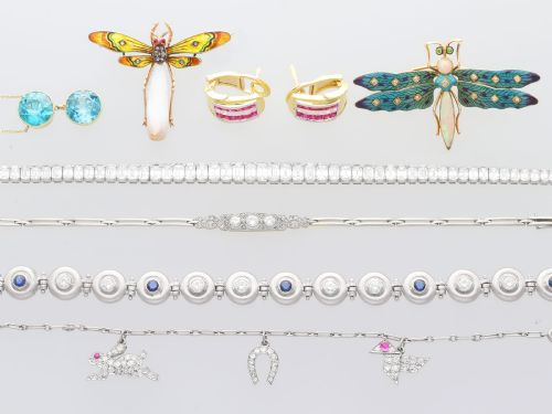 fig 6. An antique platinum link chain charm bracelet featuring diamond-set charms including a running hare, a horseshoe, and a bird with ruby accents.